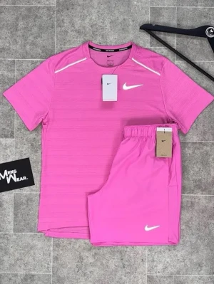 Nike rosa träningsset - Säljer ett snyggt rosa träningsset från Nike med t-shirt och shorts. T-shirten har diskreta ränder och vita detaljer på axlarna samt Nike-logga på bröstet. Shortsen har elastisk midja och vit Nike-logga på benet. Perfekt för sport och träning.