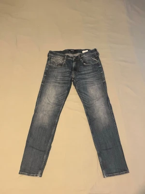 Blå slim fit jeans med slitningar - Snygga blå slim fit jeans med lätt slitna detaljer och klassisk femficksmodell. Jeansen har normal midja och raka ben. Materialet är denim i bomull med lite stretch för extra komfort. Perfekta för en avslappnad och trendig look.