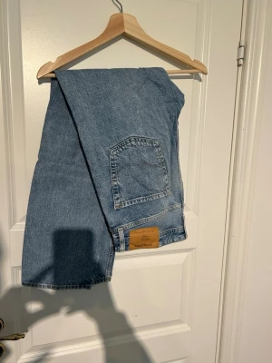 Ljusblå loose fit jeans - Säljer ett par ljusblå loose fit jeans i modellen Chris. Jeansen har klassisk femficksdesign, raka ben och är tillverkade i denim. Perfekta för en avslappnad och trendig stil.