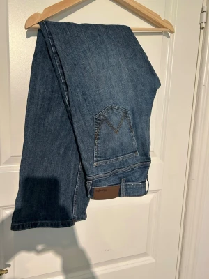 Blå raka jeans W30 L32 regular - Snygga blå jeans i regular fit med raka ben och klassisk femficksdesign. Jeansen har en diskret söm på bakfickan och är tillverkade i ett slitstarkt denimtyg. Perfekta för en avslappnad och stilren look.