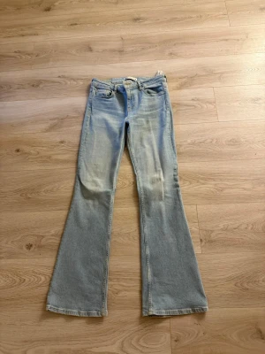 Ljusblå utsvängda jeans - Säljer ett par ljusblå jeans med utsvängda ben och klassisk femficksmodell. Jeansen har hög midja och en snygg tvätt som ger en vintagekänsla. Perfekta för dig som gillar retrostil och vill sticka ut lite extra.