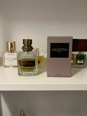 Valentino Uomo Eau de Toilette 50ml - Valentino Uomo Eau de Toilette i en lyxig, diamantmönstrad glasflaska med guldfärgad metallkork och detaljer. Doften kommer i originalkartong och flaskan har en elegant och exklusiv design som verkligen sticker ut på hyllan.
