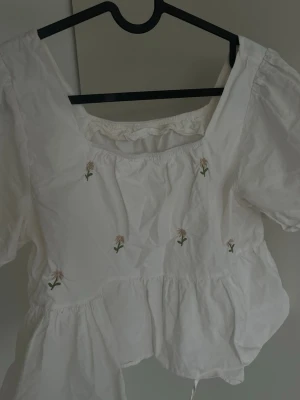 Vit blus med  blommor - Söt vit blus med puffärmar och  små blommor framtill. One size