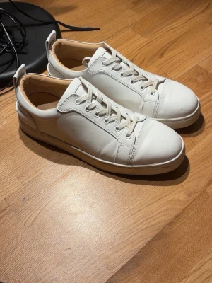 Christian louboutins stl 45 - Christian Louboutin Sneakers – White – Red Bottoms  Äkta Christian Louboutin sneakers i vit läderdesign med ikonisk röd sula. Stilrena och lyxiga passar perfekt till både casual och mer uppklädda outfits.  • Storlek: (lägg till) • Skick: Använda – viss slitage på sulor (se bilder), men ovandel i bra skick • Färg: Vit / röd sula • Material: Läder • Klassisk low-top modell  Riktigt snygga designer-sneakers som lyfter vilken outfit som helst.  Snabb frakt. Öppen för bud.