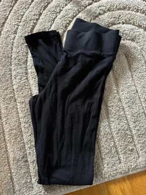 Svarta leggings med hög midja - Svarta leggings med bred, hög midja och stretchigt material. Snygg och enkel design som passar till många olika outfits. Perfekta för en avslappnad och trendig look.