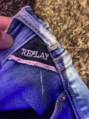 Blå jeans från Replay - Säljer ett par klassiska blå jeans från Replay. Jeansen har en snygg tvätt, silverfärgade detaljer och tydliga sömmar. Perfekta för dig som vill ha ett par stilrena och bekväma jeans i garderoben.