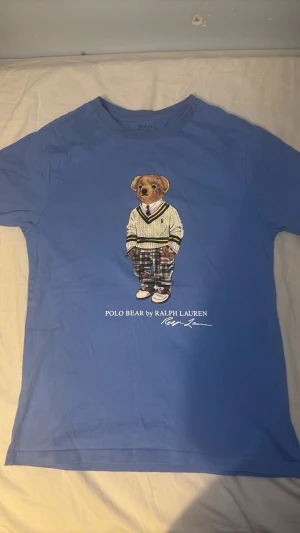  t-shirt från Ralph Lauren - Blå t-shirt från Ralph Lauren med ikoniskt Polo Bear-tryck.