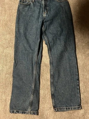 Blå raka jeans från CRUNT - Säljer ett par klassiska blå jeans från CRUNT med rak passform och fem fickor. Jeansen har en tidlös look med kontrastsömmar och knappgylf. Perfekta för dig som gillar en enkel och clean stil. Använda 1-4 gånger är som nya 