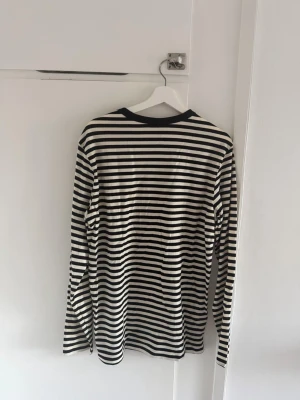 Svartvit randig långärmad topp - Säljer en svartvit långärmad topp med klassiskt horisontellt randigt mönster. Toppen har rund halsringning med svart kant och är i mjukt, bekvämt material. Perfekt för en enkel och stilren look. Tröjan är aldrig använd 