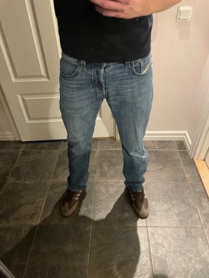 Blå raka jeans från Diesel - Säljer ett par klassiska blå jeans från Diesel med rak passform och fem fickor. Jeansen har normal midja och är tillverkade i slitstarkt denimtyg. Perfekta för en avslappnad och stilren look. Se mått på bilderna 