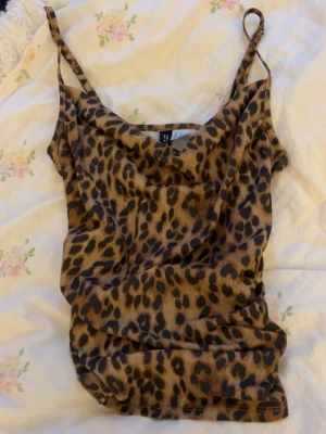 Leopardmönstrad linnetopp från H&M - Säljer en snygg leopardmönstrad linnetopp från H&M Divided. Toppen har tunna axelband och en avslappnad passform som ger en cool vibe. Perfekt för dig som vill sticka ut lite extra med ett djurmönster.