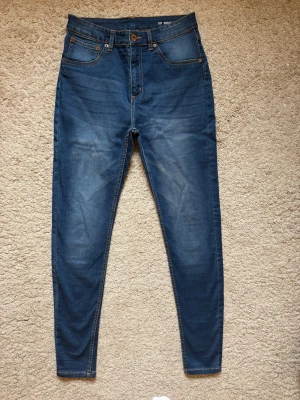 NYA jeans med hög midja - Helt nya och oanvända jeans. Färgen passar till det mesta. Klassisk femficksdesign och orangea sömmar. Jeansen har en lätt tvättad look och smal passform med hög midja. Perfekta för en trendig och avslappnad stil. Gör ett fynd!