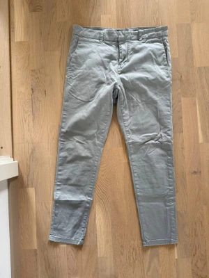Ljusgrå chinos från New Look - Snygga ljusgrå chinos från New Look med raka ben och klassisk passform. Byxorna har bälteshällor, två sidofickor och är tillverkade i ett mjukt bomullsmaterial som känns bekvämt hela dagen.