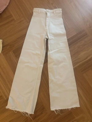 Vita Zara jeans - Säljer ett par vita jeans med hög midja och vida ben. Jeansen har lite snyggt fransiga benslut och stora stilrena bakfickor. Klassisk femficksmodell med bälteshällor och dragkedja. Materialet är kraftig denim i bomull. Endast använda 1 gång!🤍 