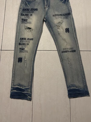AMIRI jeans - Säljer ett par ljusblå jeans från Amiri med slitningar och tryckta texter på båda benen. Jeansen har raka ben, distressed detaljer och coola broderade loggor. Perfekta för dig som gillar streetwear och vill sticka ut med unika detaljer.
