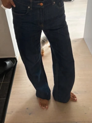 Mörkblå raka jeans med hög midja - Säljer ett par mörkblå jeans med rak passform och hög midja. Jeansen har klassiska fem fickor och stängs med knapp och dragkedja. Perfekta för en avslappnad och trendig look.