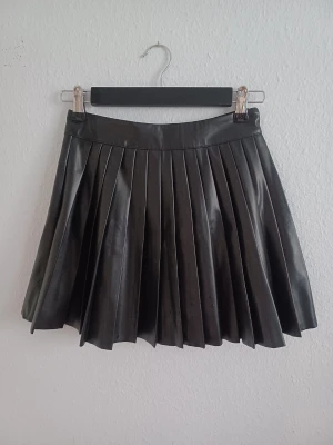 Black high waisted pleated skirt  - Stylish high-waist pleated skirt with a flattering silhouette. Versatile design that can be dressed up or down.  Size: XS / 34 Condition: Very good-worn a few times. Colour: Black Material: PU leather  Measurements: • Length: 38 cm • Waist: 63 cm  Perfect for everyday outfits, dinners, nights out or other occasions.