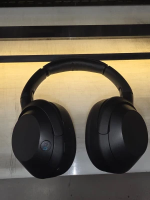 Sony ULT over-ear hörlurar - Stilrena svarta over-ear hörlurar med mjuka, vadderade kåpor och justerbart huvudband. Hörlurarna har en modern design och är tillverkade i plast och konstläder för extra komfort vid längre lyssning. Perfekta för musik, gaming eller film.