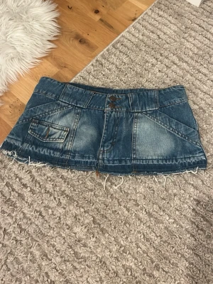 Blå jeanskortkjol med rå kant - Säljer en blå jeanskortkjol/mini skirt med slitna detaljer och rå, fransig kant nertill. Kjolen har fickor både fram och bak samt klassiska jeanssömmar.🤍