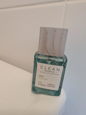 CLEAN Reserve Water Lotus parfym - Fräsch parfym från CLEAN Reserve H2EAU Collection med doften Water Lotus. Flaskan är ljusblå och fyrkantig med en stilren träfärgad kork. Eau de parfum med vattenbaserad formula, perfekt för dig som gillar lätta och naturliga dofter. 30 ml flaska, mängd kvar se bild. 
