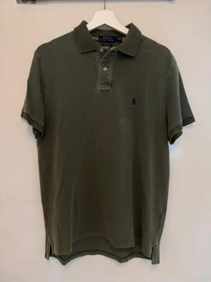 Grön pikétröja från Polo Ralph Lauren - Hej! Säljer denna coola olivgröna pikétröja från Polo Ralph Lauren med korta ärmar och krage. Tillverkad i mjuk bomull för en bekväm känsla. | Storlek: M | Skick: 9/10 | Meddela gärna vid eventuella frågor! Mvh ResellGarms 