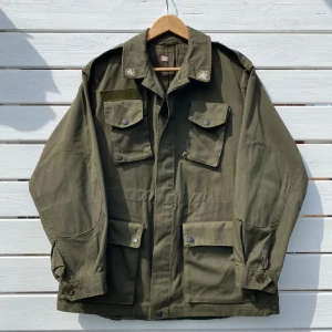 Grön overshirt äkta militärjacka - Säljer en äkta militärjacka från Italien extremt niche jacka och den är olivgrön med fyra stora fickor framtill och axelklaffar den sitter som M till L Jackan har klassisk militärstil, rak passform och knäppning med både knappar och dragkedja. Perfekt för dig som gillar utility-vibbar och streetwear.
