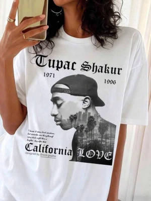 Vit Tupac Shakur California Love t-shirt - Snygg vit t-shirt med stort tryck av Tupac Shakur och texten 'California Love' framtill. T-shirten har klassisk passform, rund hals och korta ärmar. Perfekt för dig som gillar streetwear och ikoniska musikmotiv.