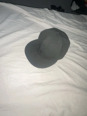 Svart New York Yankees keps - STORLEK STÅR PÅ SISTA BILDEN.Säljer en svart New York Yankees keps från New Era med broderad NY-logga framtill. Klassisk flat brim och sexpanelers design. Kepsen är helsvart och har en stilren look som passar till det mesta. Perfekt för dig som gillar streetwear och sportig stil.