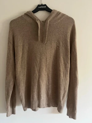 Beige merinoull hoodie  - Säljer en beige merinoull hoodie med huva och dragsnören, super bra skick knappt använd
