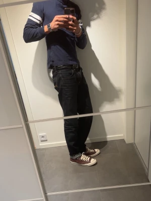 Mörkblå långärmad tröja med ränder - Snygg mörkblå långärmad tröja med två vita ränder på varje ärm. Tröjan har rund halsringning och är gjord i mjukt bomullstyg. Perfekt för en avslappnad och sportig stil.