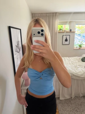 Ljusblå bandeau tubtopp - Trendig ljusblå bandeau tubtopp med twistad detalj framtill och liten cut-out. Toppen är ärmlös och croppad, perfekt för varma dagar eller som ett statement-plagg i din outfit.