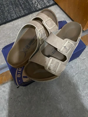 Birkenstock (Arizona) - Säljer ett par klassiska beige sandaler från Birkenstock i mjuk mocka. Perfekta för sommaren och riktigt sköna att gå i. Använt dom ungefär ett halv år