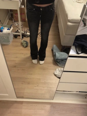 Svarta bootcut jeans från G Rise - Säljer ett par svarta bootcut jeans från Gena Jeans med hög midja och klassisk femficksmodell. Jeansen har en snygg tvättad look och är tillverkade i ett stretchigt denimtyg för skön passform. Perfekta till en avslappnad stil.