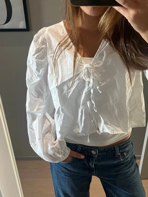Vit blus med puffärm och knytning - Säljer denna jättecoola vita lite croppade blusen🤍🤍 i jättefint skick i strl S från Gina tricot och använd 1 gång. Säljer pga att den inte kommer till användning. 