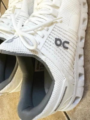 On Cloud 5 "All White" – Stl 44 - Snygga och stilrena vita sneakers från On Cloud i ventilerande meshmaterial. Skorna har On's ikoniska dämpade sula som ger otrolig komfort och grym stötdämpning hela dagen, kombinerat med riktigt snygga detaljer på sidorna. Perfekta för dig som vill ha en sportig och fräsch look. Fick dem i present men de var tyvärr för små då jag egentligen behöver storlek 45. Jag har bara försökt använda dem vid 2 korta tillfällen, så de är i absolut nyskick bortsett från lite spår på undersidan av sulan.  