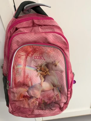 Två ryggsäckar med enhörning och drake - Säljer två coola ryggsäckar från Polo. Den ena är rosa med enhörningsmotiv, regnbåge och sagoskog. Den andra är svart och orange med ett mäktigt drakmotiv mot en eldigt röd himmel. Båda har flera fack, dragkedjor och sidofickor i mesh. Perfekta för skolan eller äventyr!