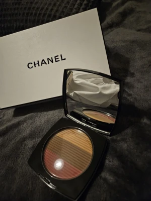 Chanel multifärgat rouge i ask - Lyxigt rouge från Chanel i en elegant fyrkantig ask med spegel. Pudret har flera nyanser i rosa, beige och brunt som kan blandas för en naturlig look. Kommer i klassisk Chanel-förpackning med logga på locket.