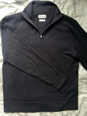 Marinblå merino halfzip These Glory Days - Snygg marinblå stickad tröja från These Glory Days i mjuk superior merinoull. Tröjan har en hög krage med halv dragkedja och långa ärmar. Perfekt för lager på lager och stilrena outfits.
