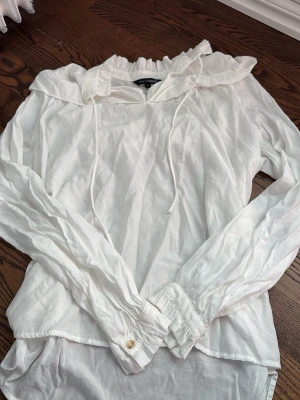 Vit blus med volangkrage och knytband - Säljer en luftig vit blus från KappAhl med lång ärm, volangkrage och knytband .Perfekt att styla med jeans eller kjol.