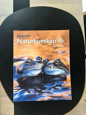 Synpunkt Naturkunskap 1b - Kursbok i naturkunskap för gymnasiet, Synpunkt Naturkunskap 1b av Anders Henriksson. Omslaget har en bild på två grodor i vatten med orange och blå toner. Perfekt för dig som läser naturkunskap 1b. Eller vill plugga upp kursen. 