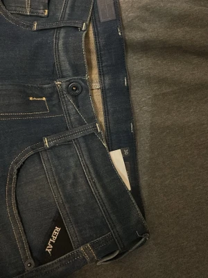 Mörkblå Replay jeans, storlek 30,34 - Snygga mörkblå jeans från Replay med klassisk femficksmodell och diskreta slitningar framtill. Jeansen har raka ben och kontrastsömmar som ger en stilren look. Tillverkade i mjukt denimtyg för skön passform. Pris kan diskuteras.