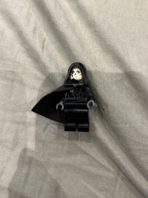 LEGO-figurer med tillbehör - Säljer LEGO-minifigurer: en svartklädd figur med huva och cape samt en lila figur med huva, blixtdetaljer och tillhörande stav. Ett skelett, en ninja och en brandman. Perfekt för dig som gillar fantasy eller samlar på LEGO. Figurerna har coola detaljer och unika färger.