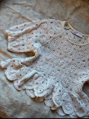 Vit spetsblus med volang från ZARA - Superfin vit blus från ZARA i spets med virkade cirkelmönster. Blusen har volangkant nedtill och vid ärmslut, samt trekvartsärm. Perfekt för dig som gillar romantisk och bohemisk stil.