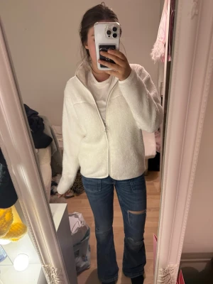 Vit teddyjacka med dragkedja storlek 160 - Storlek 160 🩷Mysig vit teddyjacka med hög krage och dragkedja framtill. Jackan har en avslappnad passform och är gjord i fluffigt teddy-material som känns riktigt skönt. Perfekt för att hålla värmen under kyliga dagar och ger en trendig look till din outfit.