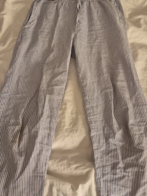Randiga pyjamasbyxor - Säljer ett par klassiska pyjamasbyxor med tunna blå och vita ränder. Byxorna har resår i midjan. 