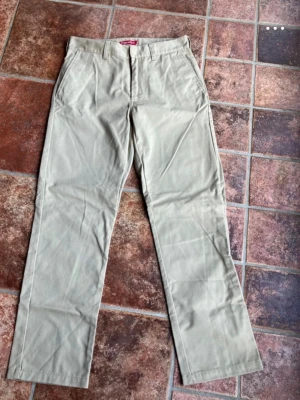 Supreme Work Pants (W30) - Säljer ett par klassiska Supreme Work Pants i en perfekt beige/khaki-färg. Modellen har Supreme's ikoniska straight fit (rak passform) och är tillverkad i en slitstark bomulls- och polyesterblandning (65% polyester, 35% bomull).Byxorna är i jättefint skick, inga fläckar eller hål. Säljes då de tyvärr inte kommer till användning längre. Innermått ben ca 75cm. Utsidan ben ca 100cm. Innermått midja runt om ca 76cm.