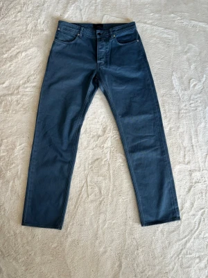 Stone Island y2k vintage jeans blå - Säljer ett par blå jeans från Stone Island med klassisk femficksmodell och raka ben. Jeansen har knappgylf och är tillverkade i slitstark denim. Perfekta för dig som gillar stilrena och tidlösa jeans.