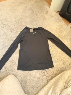 Svart långärmad topp från Only - Svart långärmad topp från Only med rund halsringning och diskret logga framtill. Tunn och mjuk kvalitet, perfekt att styla till jeans eller kjol. Enkel och stilren design som passar till många olika looks.