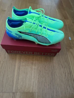 Puma Ultra neonblå fotbollsskor - Säljer ett par grymma Puma Ultra fotbollsskor i neonfärg med blå och svarta detaljer. Modell Puma Ultra 5 Ultimate FG i färgen Fizzy Apple 