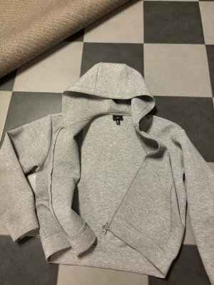 Ljusgrå hoodie med dragkedja H&M - Säljer en ljusgrå hoodie från H&M i storlek M. Hoodien har dragkedja framtill, två sidofickor och en stor huva. Tillverkad i mjukt sweatshirtmaterial som är perfekt för chill dagar. Enkel och stilren design som passar till det mesta.